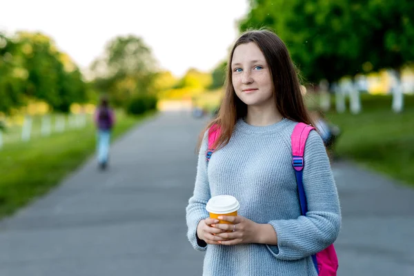 Dziewczyna jest nastolatkiem. W lecie na ulicy w mieście. Ilość wolnego miejsca dla tekstu. Trzyma kieliszek kawy lub herbaty w jego ręce. Pojęcie odpoczynku po szkole. Emocje szczęścia uśmiechów. — Zdjęcie stockowe