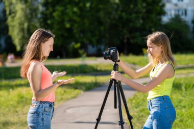 İki kız öğrenci. Doğa yazın. Fotoğraf makinesinde video kaydetmek. İnternette bir video yayını yapar. Genç blogcular ve vlogers kavramı.
