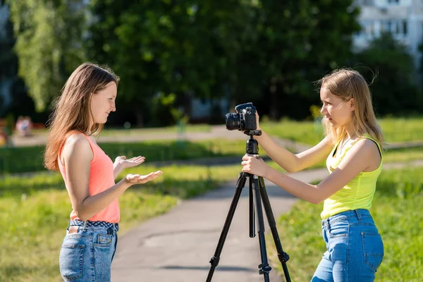 Δύο κορίτσια μαθήτρια. Το καλοκαίρι στη φύση. Εγγραφή βίντεο στη φωτογραφική μηχανή. Διεξάγει μια μετάδοση βίντεο στο διαδίκτυο. Η έννοια του νέους bloggers και vlogers. — Φωτογραφία Αρχείου