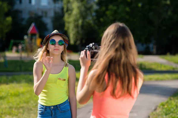 Dvě školačky v pubertě. Nahrávat video na kameře. V létě v přírodě města. Za jasného slunečného dne je blog nebo vlog. — Stock fotografie