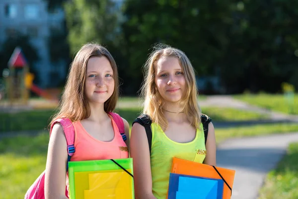2 つの若い女子学生。自然の中の夏。幸せな笑みを浮かべてください。学校に行く準備ができてイム。両手ノートとフォルダー. — ストック写真