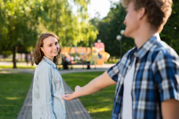 V létě v parku v přírodě. Mladík se seznámí s dívkou. Roztáhne jí natáhla ruku po komunikaci. Dívka úsměvy šťastně říká, že ano. Randění ve městě. — Stock fotografie