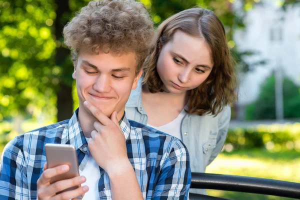 Genç bir adam seyir telefon bir mesaj okuyor. Bir adamla bir kız doğa yaz. Arkadan kız casuslar. Güvensizlik kavramı. Muhatap gözetleme.