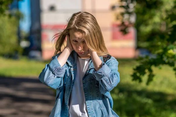 Teenage girl in summer outdoors. The palms of his hands close his ears. The concept of insult a misunderstanding, a loud noise. Emotions of discontent, bad behavior, sad and resentful child. — Stock Photo, Image