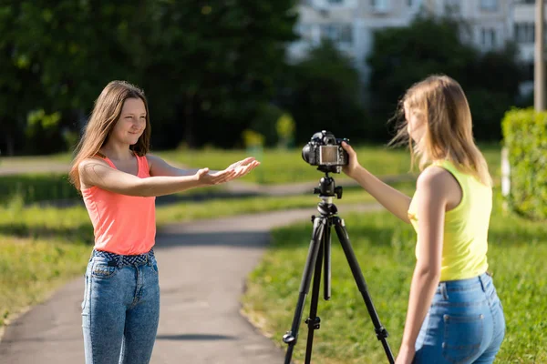 Two girls are students. Summer in nature. Conduct a conversation. Record vlog and blog. Record video lesson for Internet. Use camera with tripod.