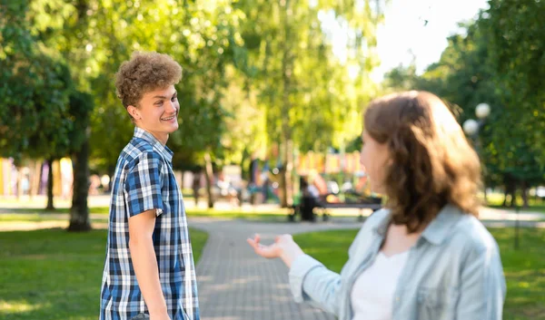 Seorang siswa perempuan bertemu dengan seorang pria muda di taman. Di musim panas di kota secara alami. Dia mengulurkan tangannya untuk komunikasi. Pria itu tersenyum dengan gembira dan berkata Ya. Kenalan di kota. . — Stok Foto