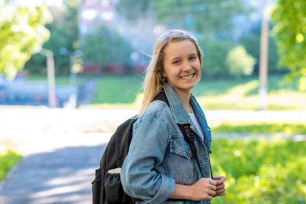 Nastolatek uczennica dziewczyna. Lato w przyrodzie. Happy dodać za swój plecak. Ilość wolnego miejsca dla tekstu. — Zdjęcie stockowe