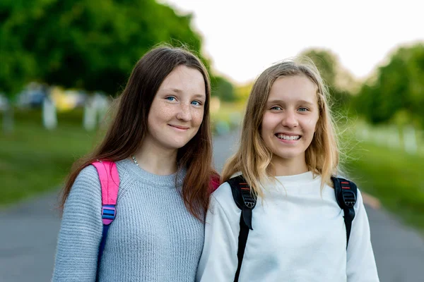 Twee meisjes schoolmeisje tiener, in de zomer na school in de natuur. Om te poseren voor de camera. Emoties van vreugde en plezier. Het concept van rust na school op een pauze is. — Stockfoto