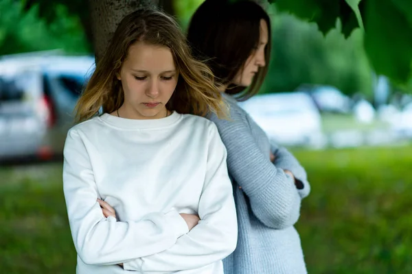 Dua gadis sekolahan remaja, di musim panas di taman dekat pohon. Konsep pertengkaran, masalah, kebencian, ketidakpuasan. Emosi frustrasi, kesedihan, kekecewaan, suasana hati yang buruk . — Stok Foto