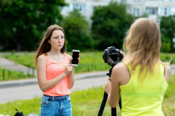 Little girls dziewczyny. Latem w parku w przyrodzie. Zapisuje wideo do kamery. W jego rękach posiada smartfona. Dwa blogerów uczennica na ulicy. — Zdjęcie stockowe