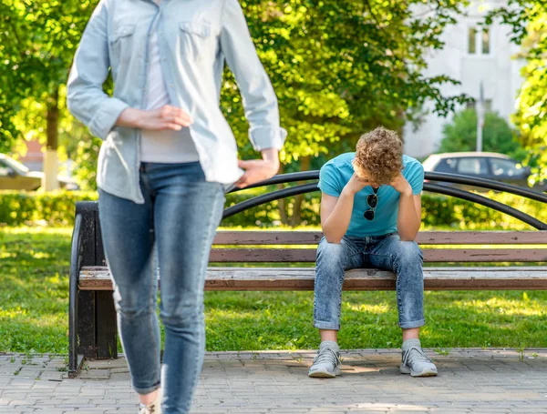 Close-up of a guy sitting crying on bench. The concept is a problem in the family. A break up. The girl leaves the guy. Summer in nature. — Stock Photo, Image