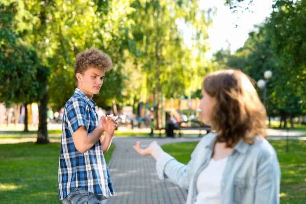 Chica en verano en una naturaleza parque. Intenta familiarizarse con un joven. El tipo hace gestos para mostrar que no. Reticencia a hablar. El concepto de citas en la ciudad . —  Fotos de Stock