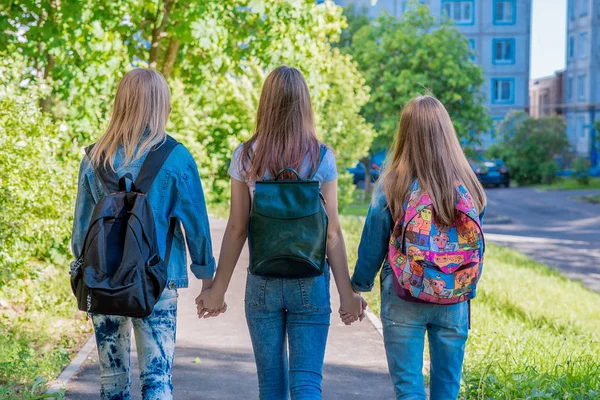 Três meninas adolescente estudante segurando as mãos uns dos outros. No verão no parque. Visão traseira, voltando para casa. O conceito é melhores amigos, namoradas da escola . — Fotografia de Stock