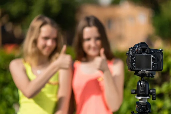 Duas adolescentes, no verão no parque, estão gravando vídeo na câmera. Desfocado espaço livre de fundo para texto . — Fotografia de Stock