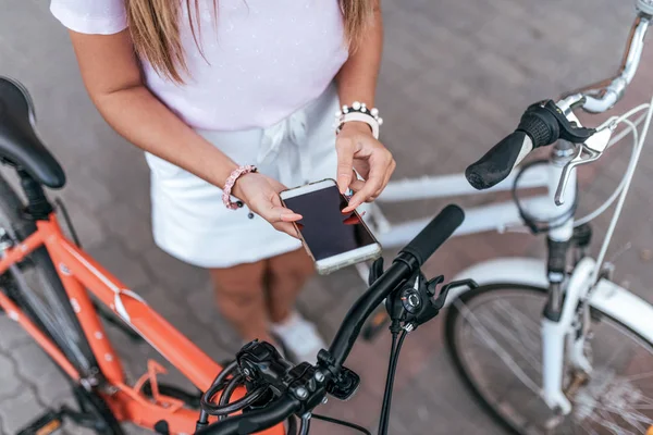 Das Mädchen wirft auf Telefon, Fernbedienung Fahrrad. entfernt sich vom Parkplatz, nutzt die Internet-Anwendung für die Übergabe der Sicherheit an das Schloss. — Stockfoto