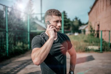 Adam telefonu tutuyor. Yazında park görüşmeleri bir cep telefonu. Şehirde yaz eğitim atlet.
