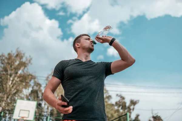 Ein Mann trinkt Wasser aus einer Flasche. — Stockfoto