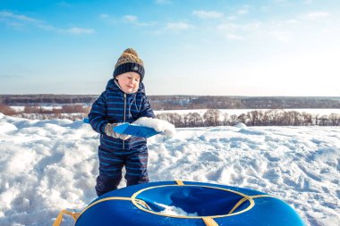 Küçük bir çocuk 3 yıllık eski şehir, kışın, kar kazılar, boru içine dökülen bir kürekle oynar. Mutlu neşeli parlak güneşli bir günde.