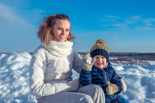 Mum dengan anak kecil dari 3 tahun, pada hari yang cerah di sebuah kota di musim dingin. Bermain bola salju. Happy tersenyum santai di alam. Keluarga bahagia di udara segar . — Stok Foto