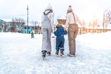 Küçük bir çocuk ile 3-5 yaşında iki kız arkadaşım binmek. Kışın, şehirde, Eğitmenler paten üzerinde durmak genç oğulları Tren.