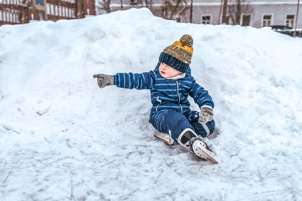 Little boy 3-5 years old, sitting on snow in the skates. In the winter in the city on the site for skating. — 图库照片