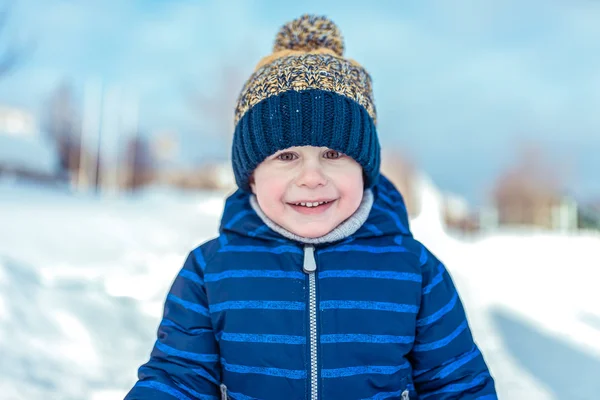 一个4-6 的小男孩的肖像。快乐的微笑在冬天的帽子, 蓝色的工作服。快乐的男婴特写镜头, 清晨在城市里. — 图库照片