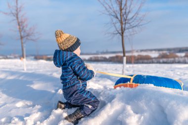 Küçük çocuk tüp çeker. Bir spatula tutarak ellerinde. Kışın, şehrin bir roller coaster üzerinde mutlu bir çocuk çalış.