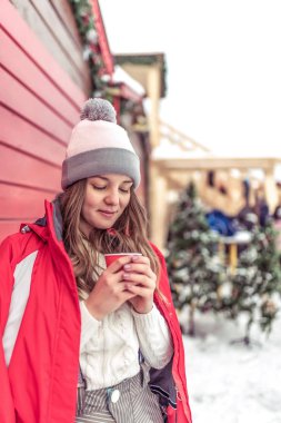 Güzel genç kız hakkında bir kupa sıcak kahve veya çay ile ısınma. Bir kış kasabasında kahvaltı. Kış günü sırasında soğuk havalarda ısındı.