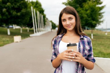 Genç kız 10-14 yaş civarında, yaz aylarında şehir parkında duran bir fincan kahve ya da çay onun elinde tutan. Yaz, mutlu gülümsüyor. Açık rekreasyon kavramı. Metin için boş alan.