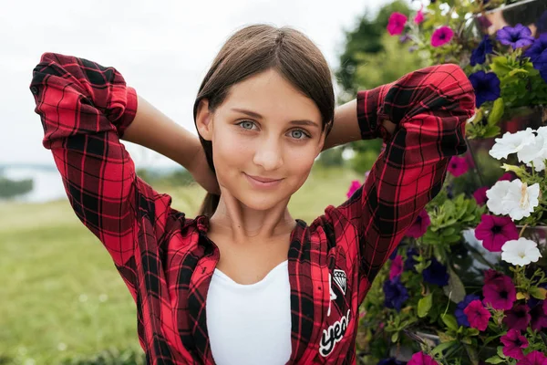 Het tiener meisje in een rood shirt, in de zomer in het park rechtzetten haar, outdoor recreatie, close-up portret. — Stockfoto
