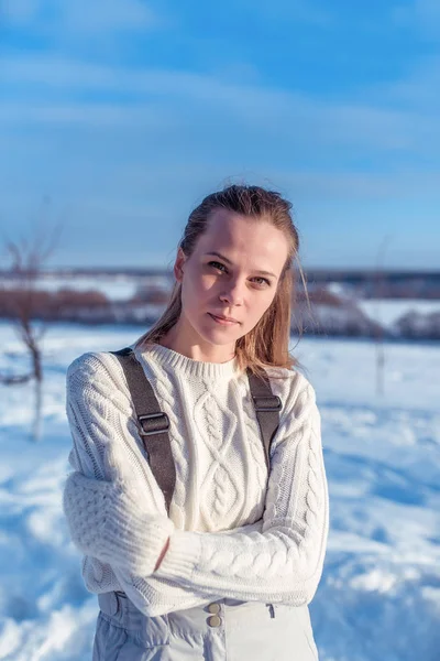 Portrét mladé dívky v bílém svetru a rukavice. V zimě na venkově v neformální oblečení. Šťastná žena odpočívá na povaze během zimního dne. — Stock fotografie