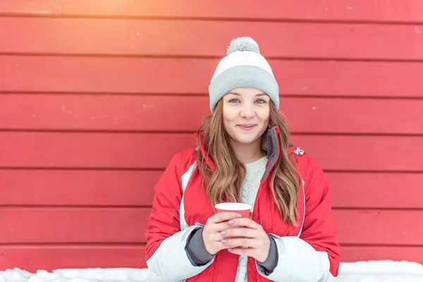 Chica feliz sonriendo emocionalmente sosteniendo una taza de café o té. Espacio libre para texto. Se calienta sobre una taza con una bebida caliente. Mujer descansando en un evento en invierno en la ciudad . — Foto de Stock