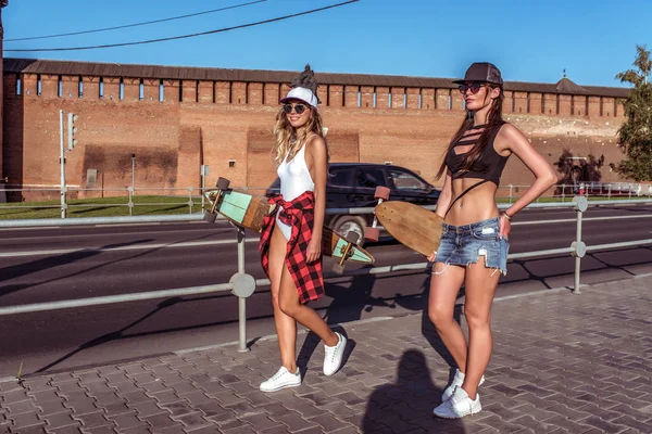 Pacar gadis cantik di kota musim panas. Berjalan dengan skateboard longboard. Dengan rambut panjang dan topi baseball senyum bahagia. Ruang kosong untuk teks. Di latar belakang jalan dengan mobil . — Stok Foto