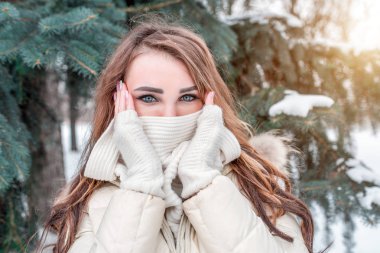 Güzel kız kış orman, arka plan Ladin Noel ağacı. Örme eşarp, doğada kışın şiddetli Don sarılmış. Bir kadının elleriyle yüzünü kapsar, kış soğuk günde doğa kadar ısıtır.