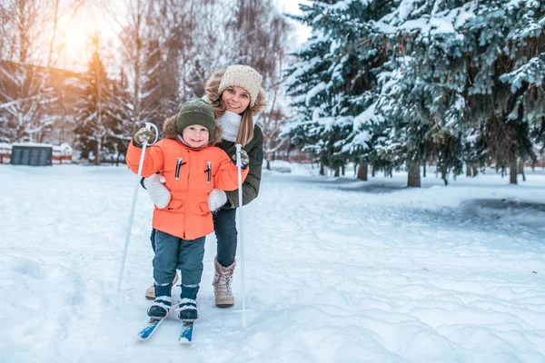 Mooie en jonge moeder leert om te skiën, jongetje 3-5 jaar oud, zoon in winterkleren. In de winter, in het bos in het resort waar er veel sneeuw. Vrije ruimte voor tekst. — Stockfoto