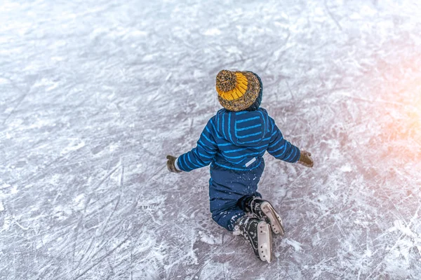 Niño de 2-3 años, con falda, cayó sobre el hielo de sus patines. Concepto primera lección de patinaje de apoyo, fracaso y caída, aprender a practicar deportes y estilo de vida activo. Espacio libre para texto . — Foto de Stock