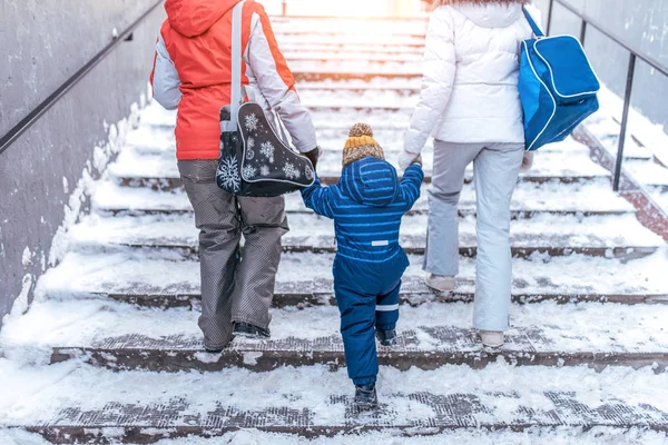Çocuk evlat 2-3 yıl için el ile holding, kış boyunca bir Altgeçit merdiven Anaokulundan dönen kız arkadaşı Anne ile bir kadın anne. Arkadan Görünüm. Kavram yardım bakım destek veli çocuk bakımı.