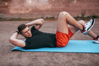 Oyun mindere erkek atlet yaz aylarında. Karın kasları trenler, büküm yapar. Aktif yaşam tarzı fitness, egzersiz sokakta. Güçlü ve güçlü adam.