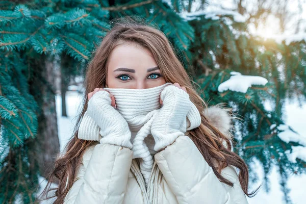 Una hermosa chica cubre su cara con una bufanda blanca, primer plano de la mirada y el ojo. Manoplas blancas de maquillaje casual. Confianza en mirar las emociones del frío y el calentamiento en un día helado en el aire fresco . — Foto de Stock