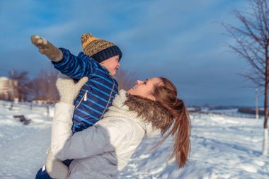 Genç bir anne bebek çocuk ile kış şehirde 2-3 yıl oynar. Mutlu gülümseyerek ve birbirimizi. Mutlu bir aile doğa sıcak giysiler giyen kışın çalış. Eğleniyor hafta sonu yürüyüş sokak.