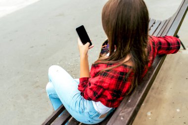 Kız kız öğrenci 10-15 yaşında, yaz şehir okul dersleri sonra dinlenme. Tezgah elinde telefon, online Internet uygulaması, sosyal ağlar yazışma sohbet. Arka arka plan asfalt görüntülemek.