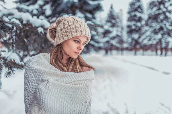 Beautiful and young girl wrapped in a white scarf and plaid. Gently and emotionally looking away. Free space for text. Winter evening in the forest, the romance of a cold day in the fresh air. — Stock Photo, Image