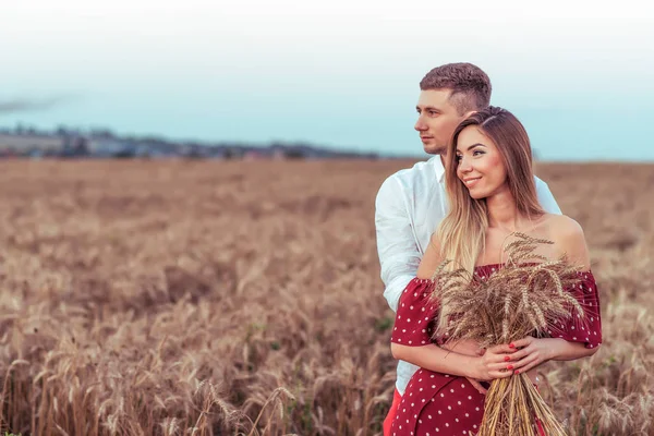 Pareja joven de campo de trigo, abrazando, en verano en la aldea, en manos de trigo. Emociones de alegría, sonrisas de felicidad y amor. Espacio libre para texto. Concepto de cuidado fuerte tradición familiar, la generación . — Foto de Stock