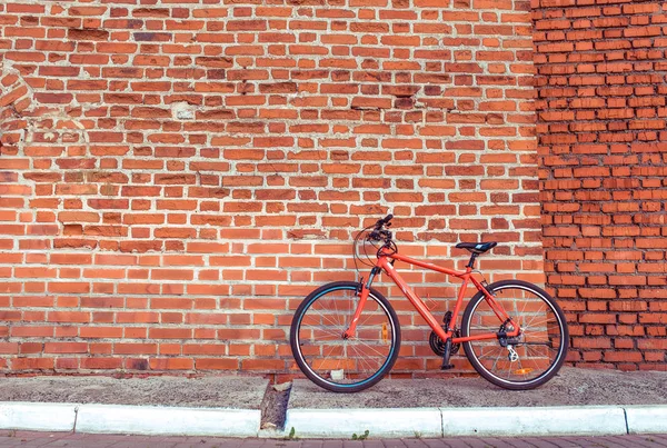 레드 스포츠 자전거 스탠드는 벽돌 벽 바탕에. 텍스트에 대 한 여유 공간입니다. 여유 공간, 도시에는 건강 한 라이프 스타일의 개념. 주차장 및 피트 니스, 스포츠 도시에 남아. — 스톡 사진