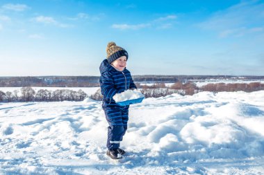Küçük bir çocuk 3-5 yıl yaşlı, doğada, mutlu kışın gülümseyerek, kar ve kar sürüklenir elinde bir kürek ile yürüme. Duygular sevinç ve bir soğuk kış gününde eğlenceli, Açık Rekreasyon.