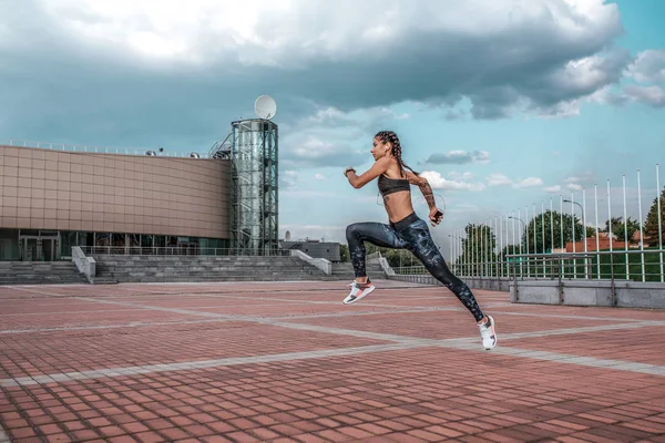 Salto em altura. Menina atlética jovem correndo corrida de manhã treino de fitness sportswear leggings e top. Telefone escuta fones de ouvido de música. Summer city workout, aplicação online playlist Internet. Espaço livre . — Fotografia de Stock