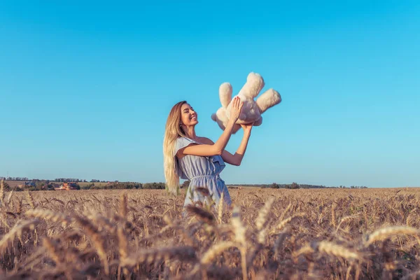 Gadis cantik dan muda bermain di musim panas di ladang gandum. Melempar boneka beruang mainan. Emosi kegembiraan permainan dan kebahagiaan. Ruang kosong untuk teks. Lucu lelucon dan permainan pada akhir pekan setelah pesta . — Stok Foto