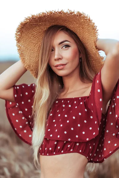 Retrato de uma menina bonita em um vestido vermelho e chapéu de palha, no verão no campo. Cabelo longo pele bronzeada e maquiagem casual. Emoções apreciando o passeio e ar fresco na natureza. Slim figura de uma mulher . — Fotografia de Stock