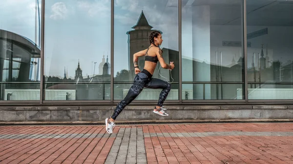 Motivation in motion girl jump, active lifestyle, jogging and running in city in summer in fresh air. The concept of strength, endurance, slim figure of a woman. Sport muscles in motion. Free space.