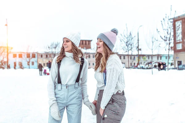 Chicas felices se regocijan en el invierno en la pista. Sonríen y se ríen en invierno en el resort, los fines de semana en una pista de patinaje pública, con ropa de abrigo y sombreros . —  Fotos de Stock